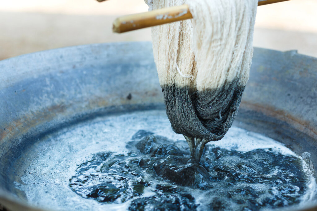 Yarn being dipped into a dye pot.