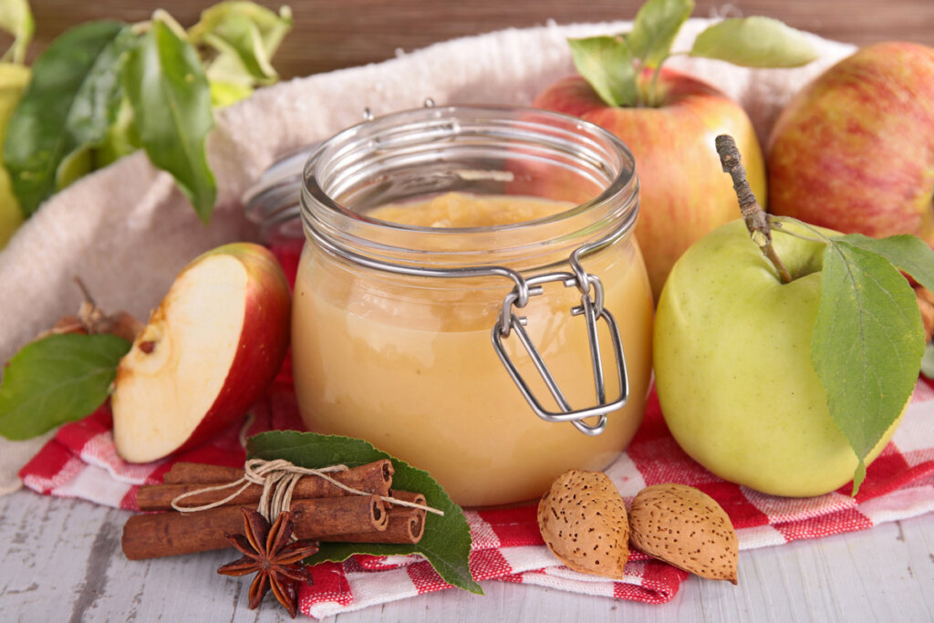 Homemade applesauce in a swing top jar with apples around it.