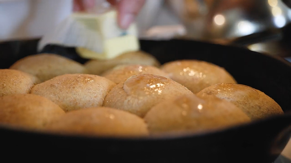 Freshly baked rolls being slathered with butter.