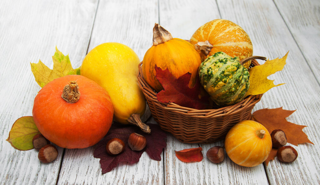 Decorative pumpkins displayed on a white washed wooden table top.