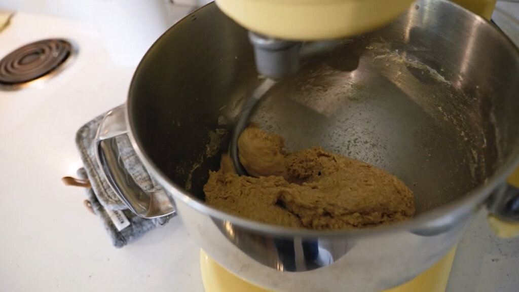 A light yellow KitchenAid mixer mixing dough for rolls.