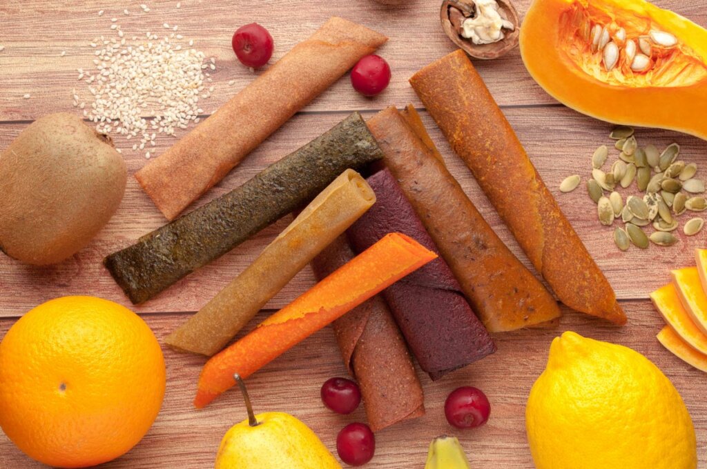 Various flavors of pumpkin fruit leather with different fruit and nuts surrounding.