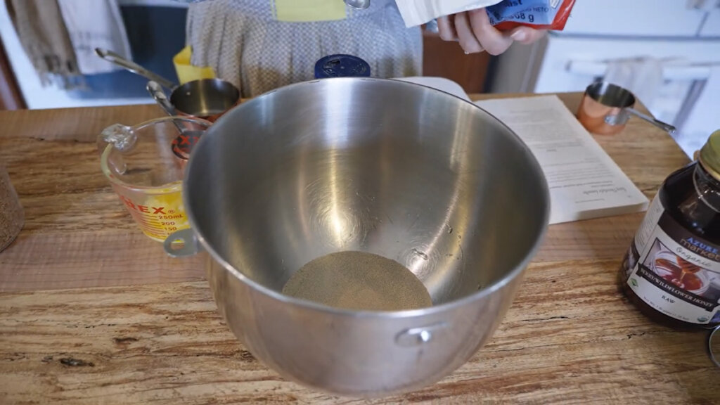 Stainless steel mixing bowl with water and yeast.