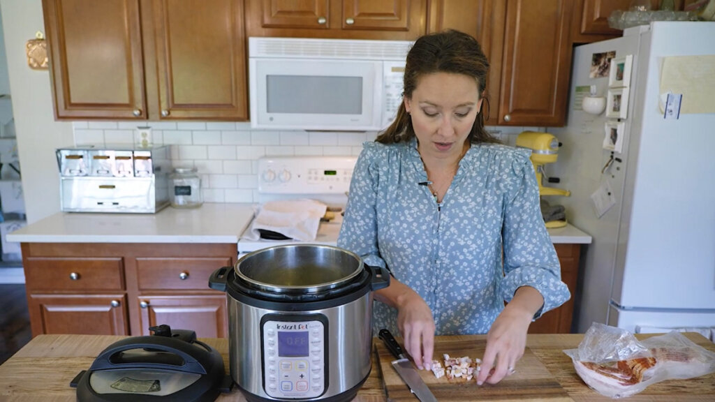 A woman chopping bacon and adding it to an Instant Pot.