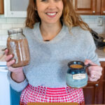 Pinterest pin for homemade hot cocoa mix, woman holding up a jar of hot cocoa mix and a mug of hot chocolate.