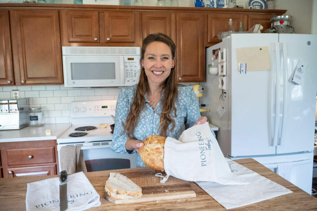 A woman putting a loaf of artisan bread into a linen bread bag.