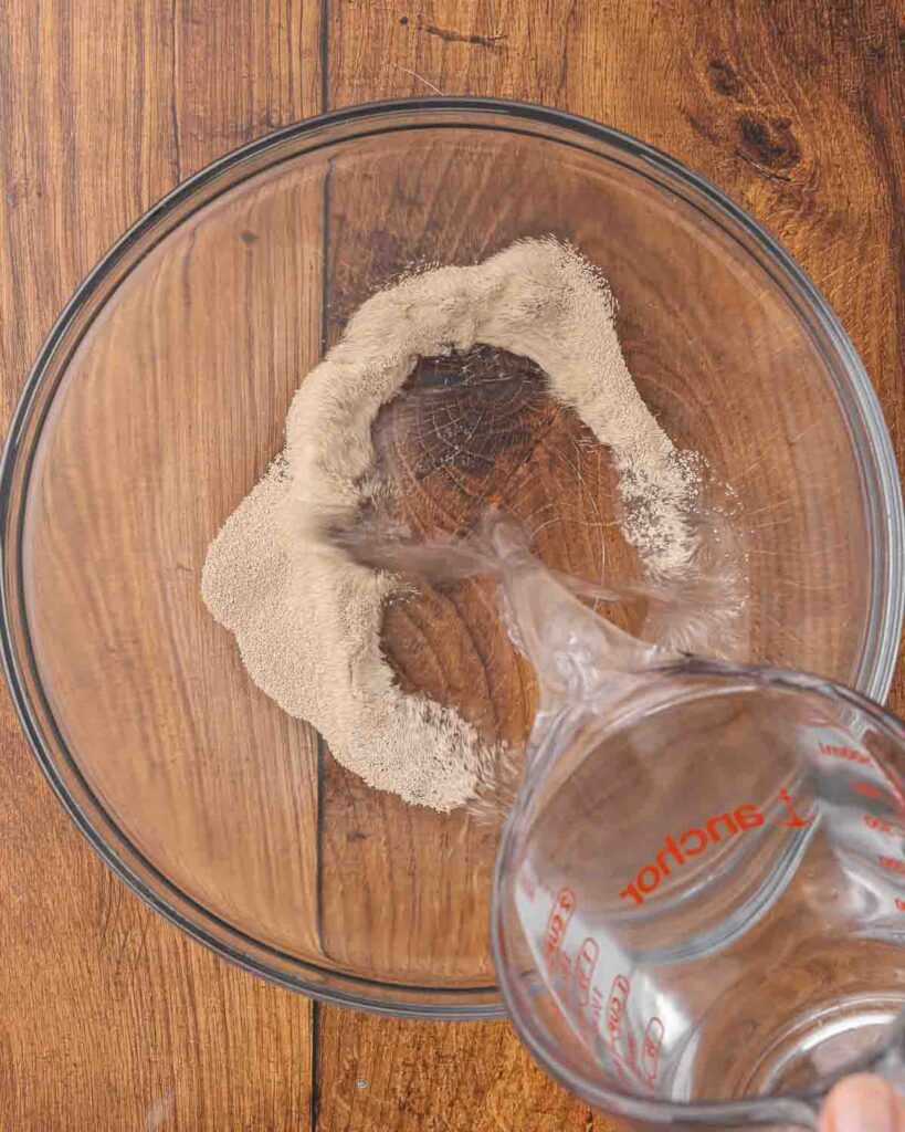 Pouring water in a bowl with yeast.