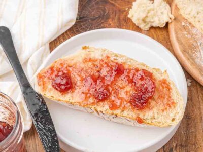 A slice of no knead bread with strawberry jam.