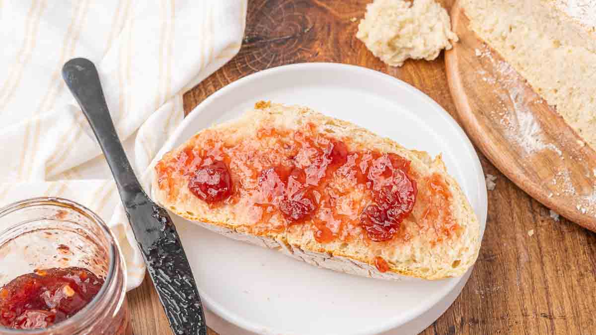 A slice of no knead bread with strawberry jam.