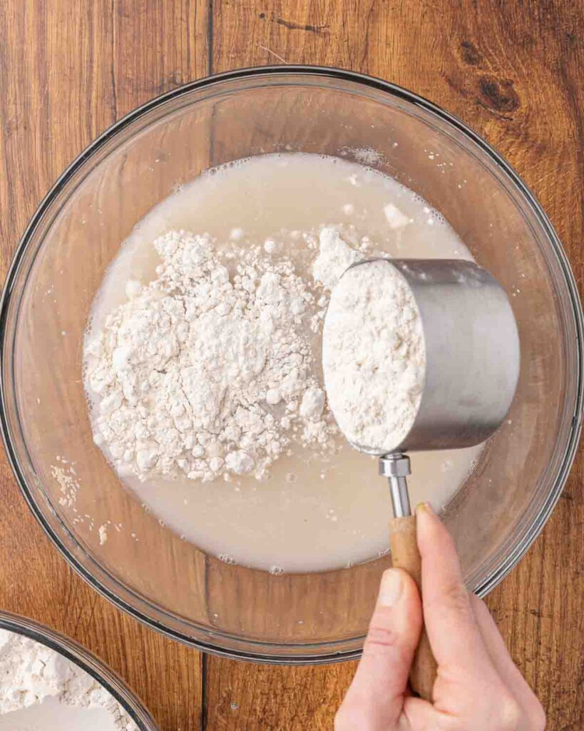 Adding flour to a bowl of yeast dissolved in water.