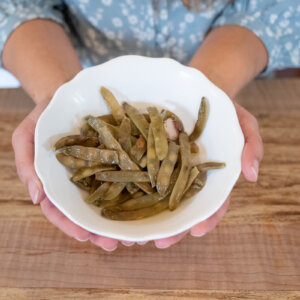 A white bowl of cooked green beans.