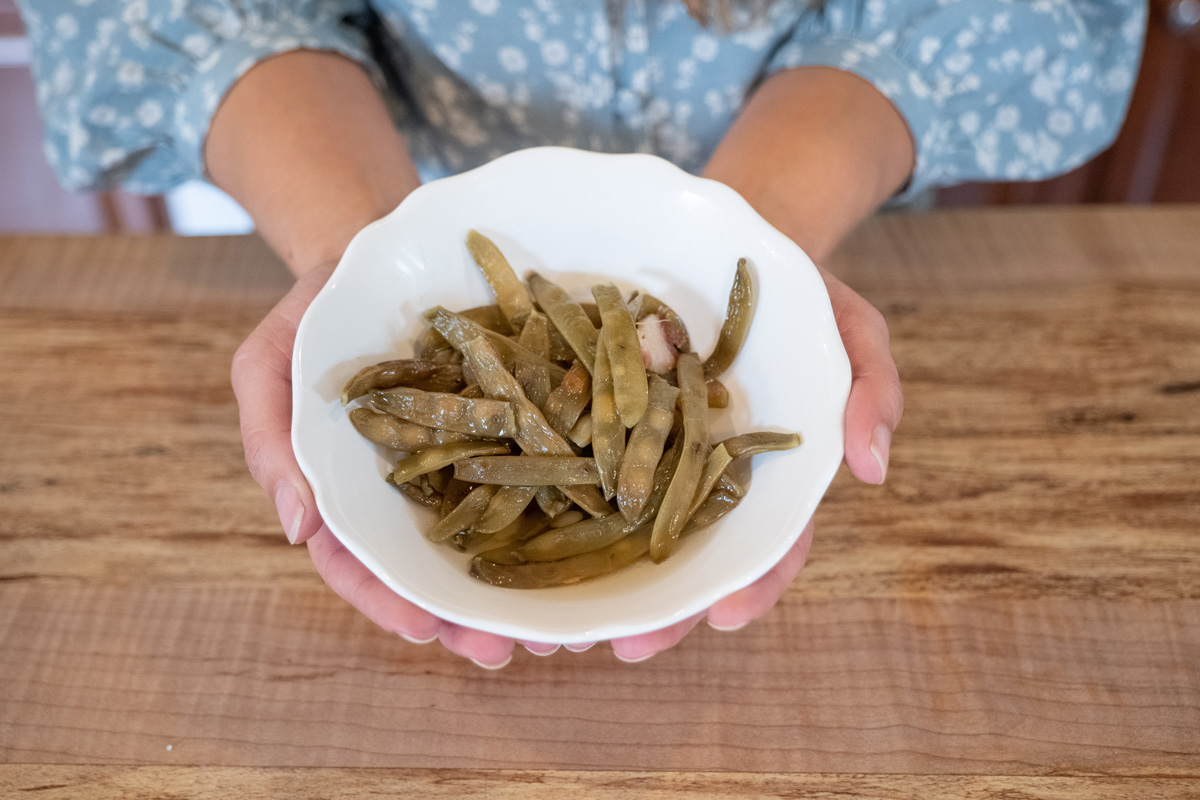 A white bowl of cooked green beans.