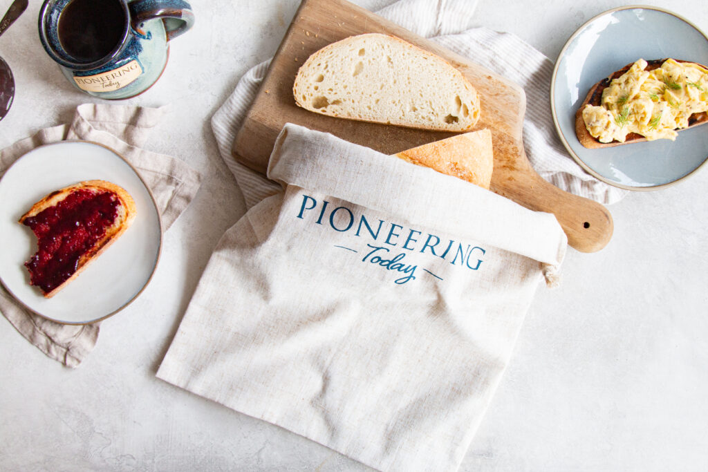 Sliced loaf of bread in linen bread bag on cutting board