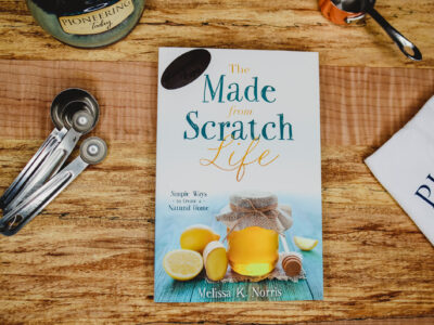 Made-from-Scratch Life Book with Autographed Copy Sticker on wooden counter with mug, towel, and measuring spoons