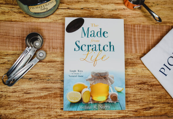 Made-from-Scratch Life Book with Autographed Copy Sticker on wooden counter with mug, towel, and measuring spoons