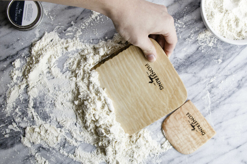 Wooden maple bench knife scraping flour and dough off counter top