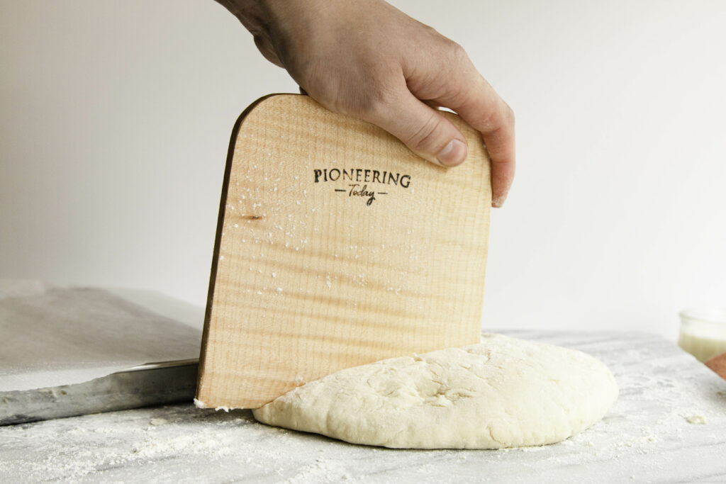 wooden figured maple bench knife cutting pastry dough on counter top