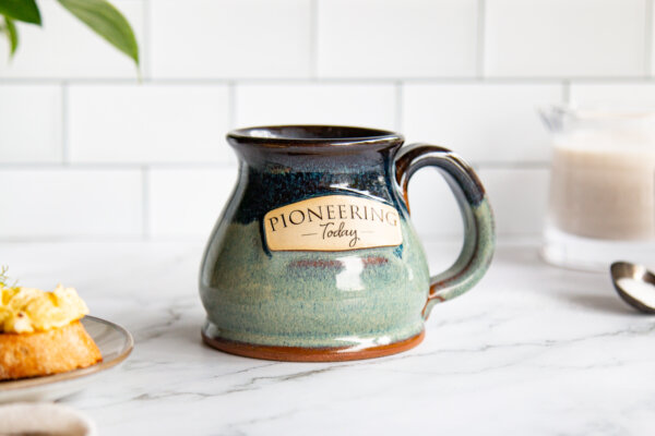 Glazed mug with "pioneering today" stamped on it.