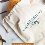 Pinterest pin for how to store bread. Image of homemade bread in a linen bread bag.