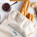 Pinterest pin for how to store bread. Image of homemade bread in a linen bread bag.