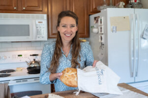 A woman sliding a loaf of homemade bread into a linen bread bag.