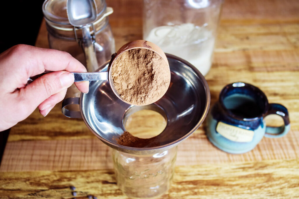Assembling hot cocoa powder mix in a glass mason jar.