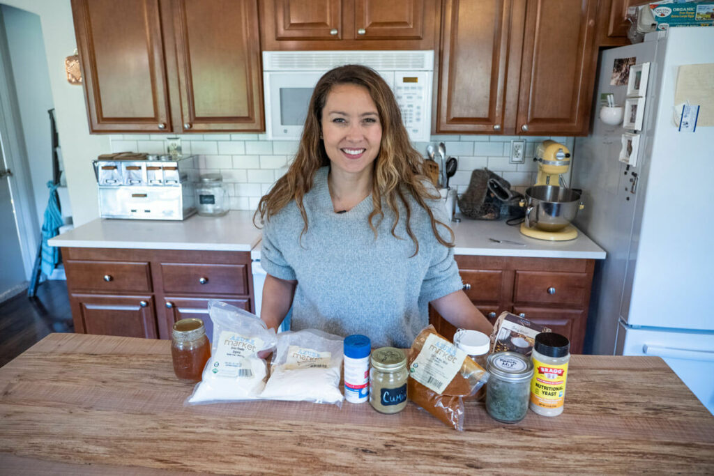 A woman standing behind a counter filled with kitchen pantry staples.