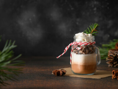 homemade hot cocoa mix in a mason jar with red and white twine and pine cones on table top