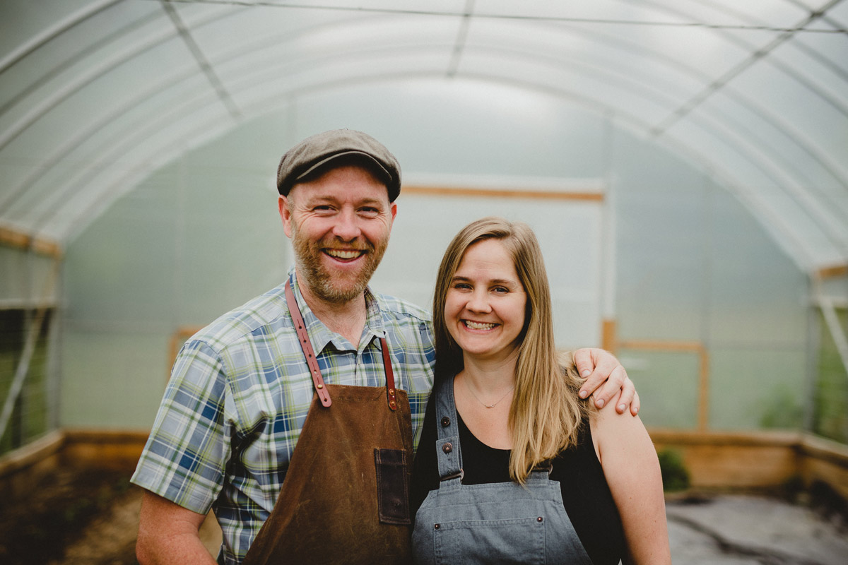 A husband and wife standing in a high tunnel.