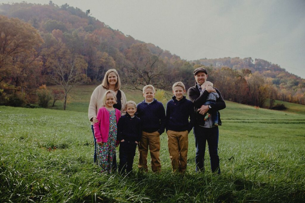 Justin and Rebekah Rhodes and family standing in a field.