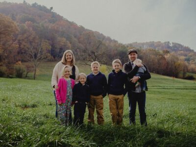 Justin and Rebekah Rhodes and family standing in a field.
