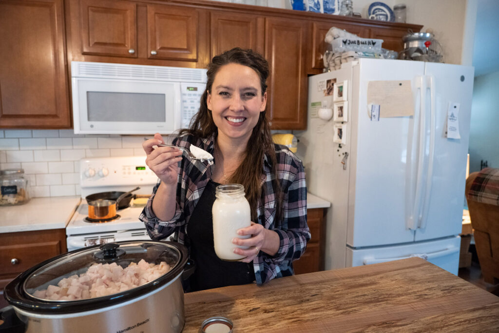 A woman scooping lard out of a jar.