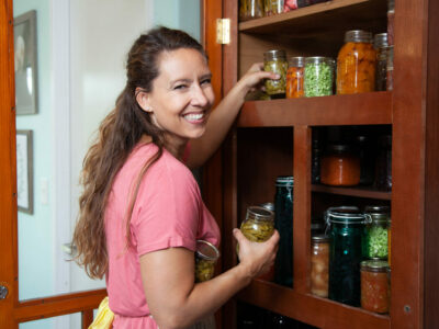A woman pulling out home canned foods from a pantry.