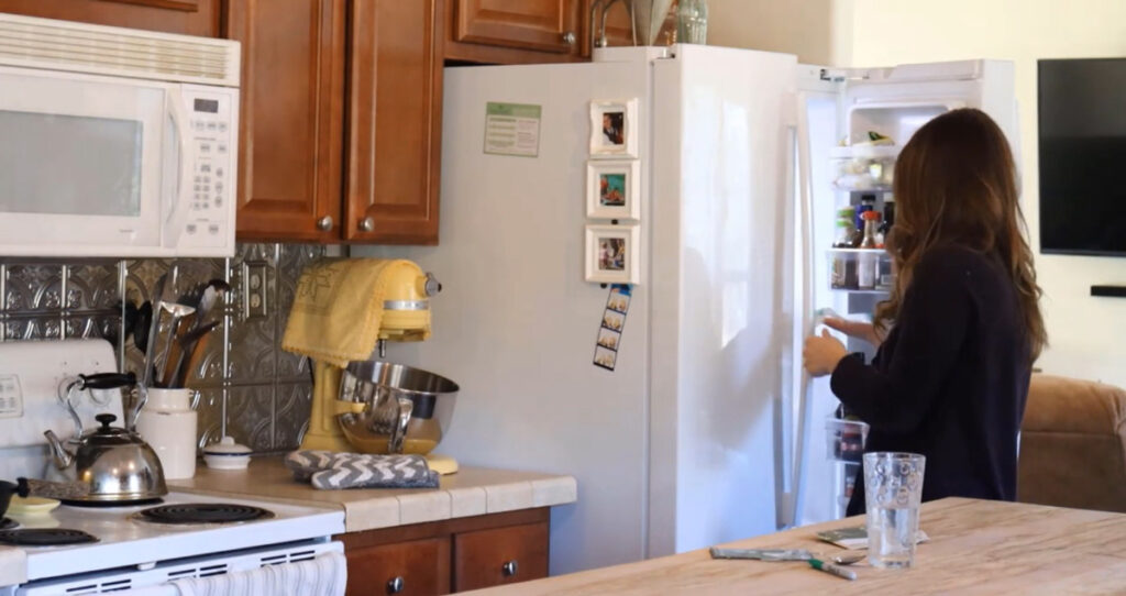 A woman putting ziplock bags of seeds into the refrigerator for cold stratification.