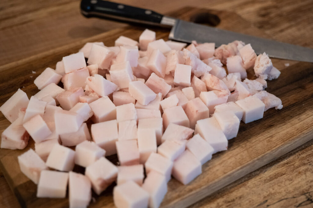 Chopped lard on a cutting board with knife.