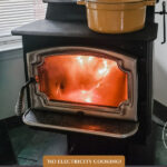 Pinterest pin for how to cook on a woodstove. Image of a pot of food on a woodstove.