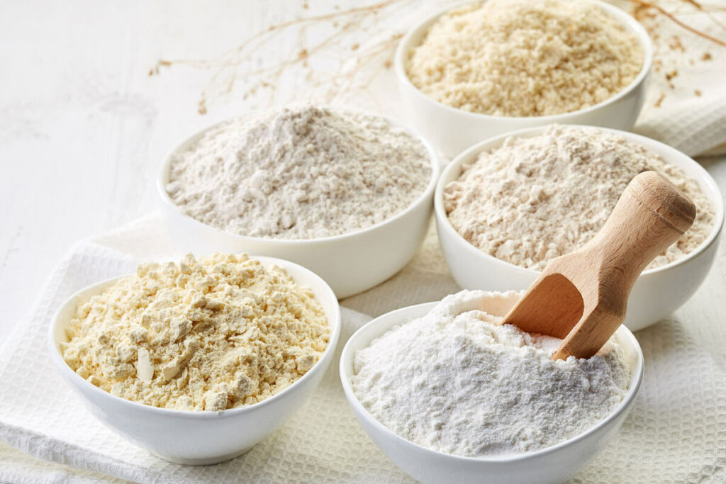 Five white bowls filled with various gluten free flours.