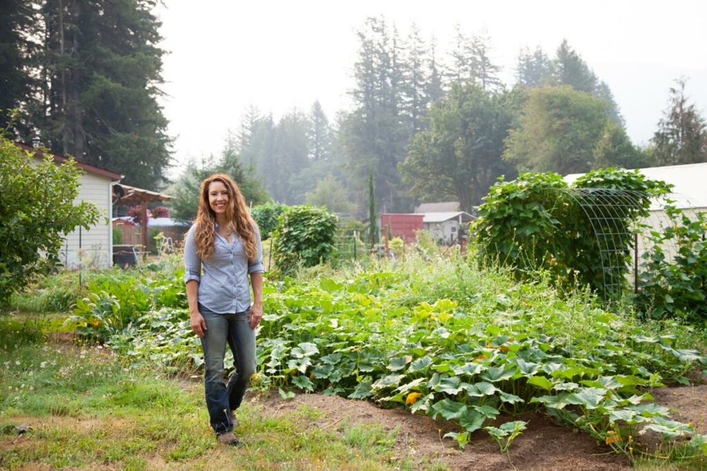 A woman standing in front of a large vegetable garden.