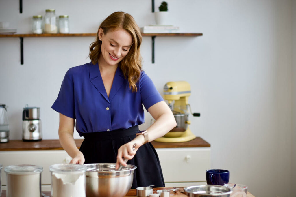 A woman baking in the kitchen, stirring with a wooden spoon.