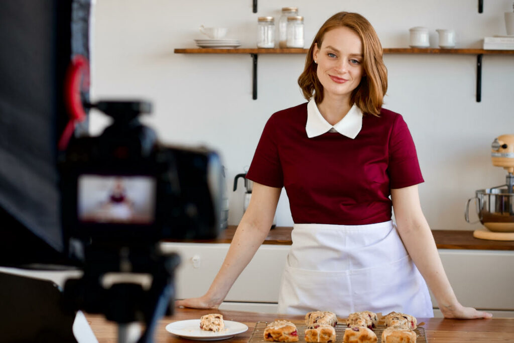 A woman in the kitchen standing behind pastries.