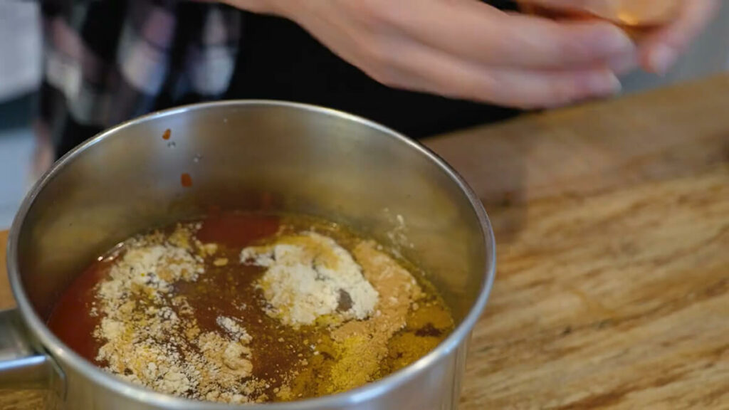 Seasonings in a pot with tomato soup ingredients.