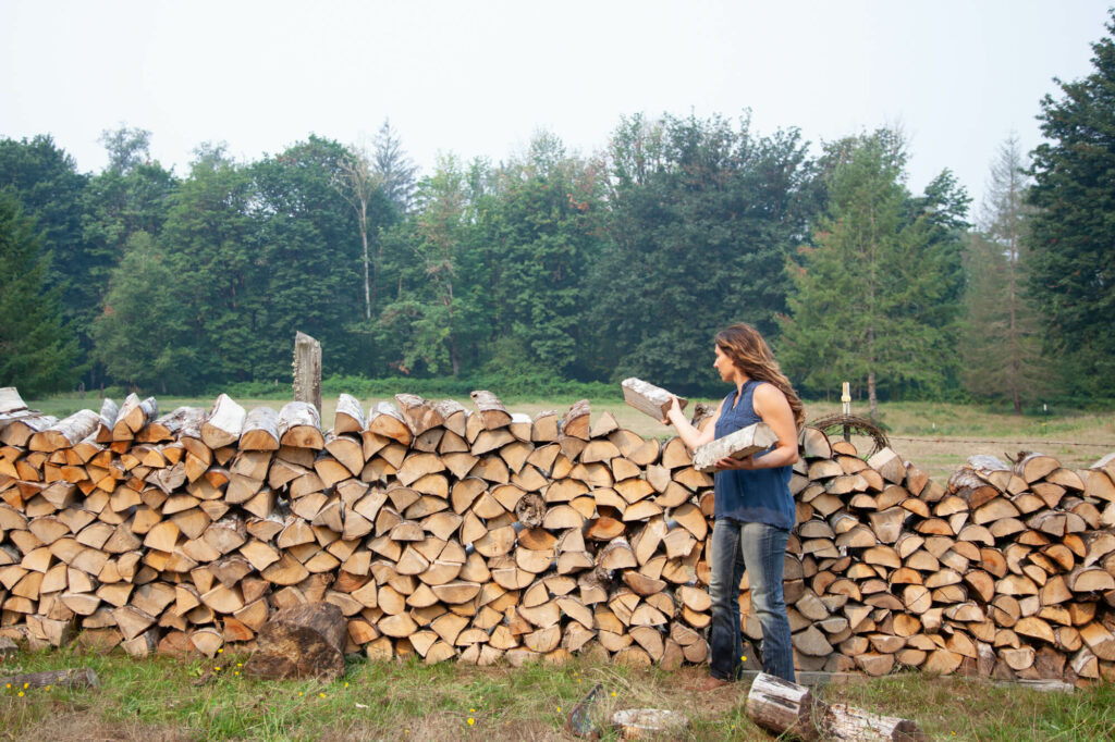 woman stacking firewood in field to dry