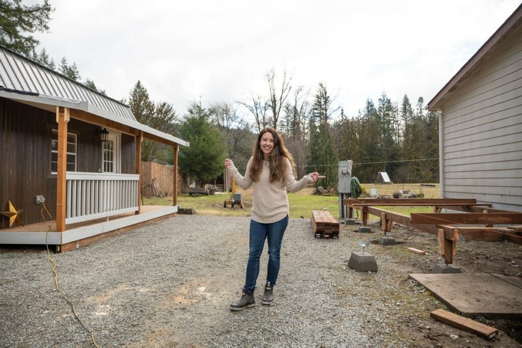 A woman pointing to a shed and the beginning of a house addition.