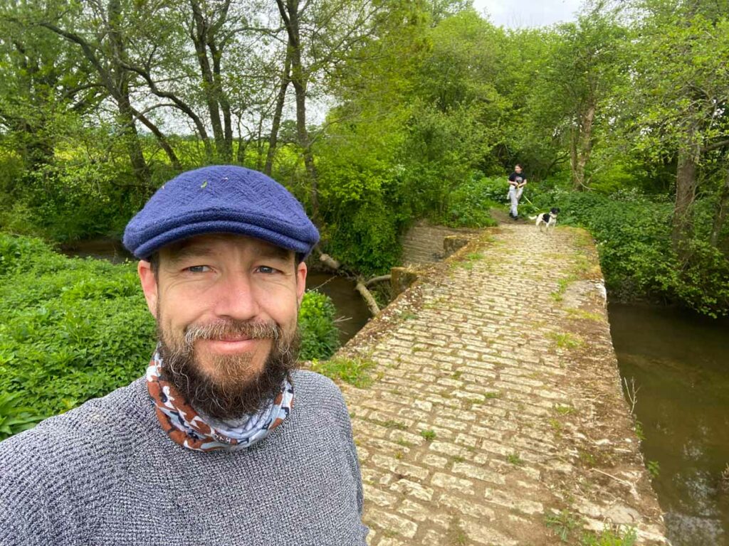 A man standing near a stone bridge.