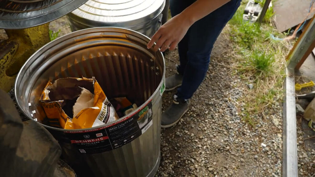 A bag of dog food in a metal trash can.