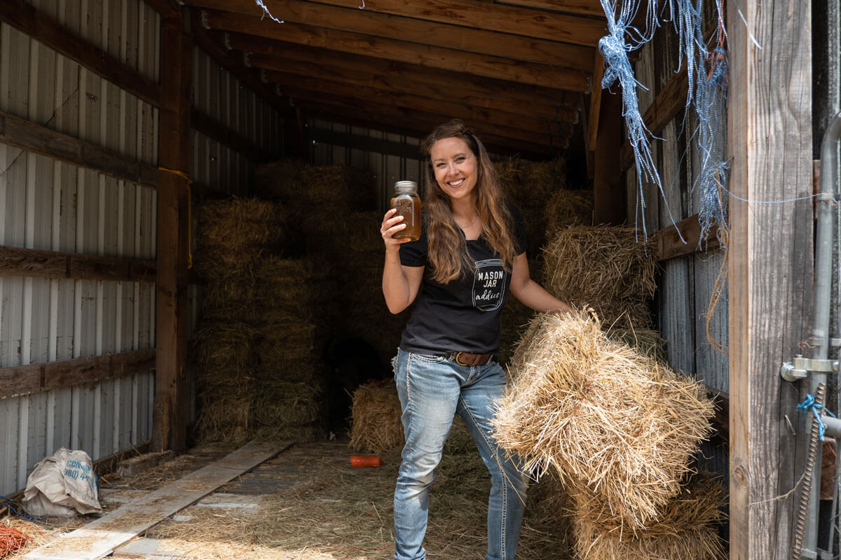 A woman hauling a bale of hay holding up haymakers punch.