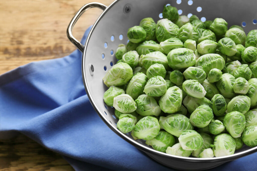 Brussels sprouts in a colander on a blue towel.