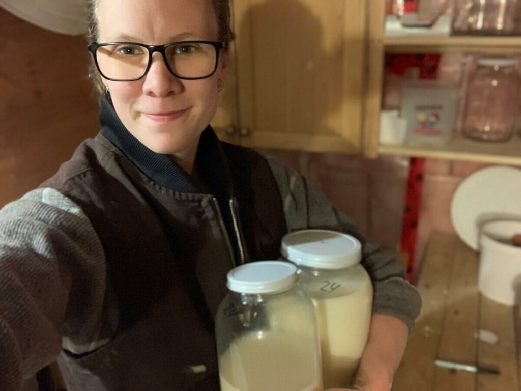 A woman holding two jars of raw milk.
