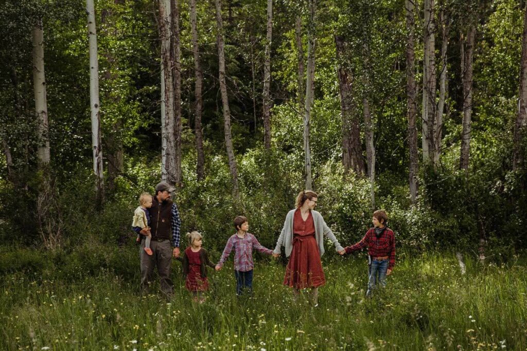 A family holding hands in the woods.