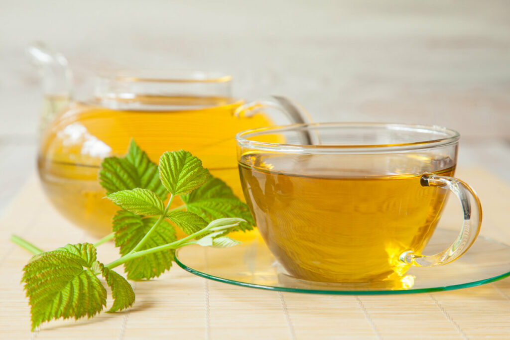 Raspberry leaves next to a cup of tea.